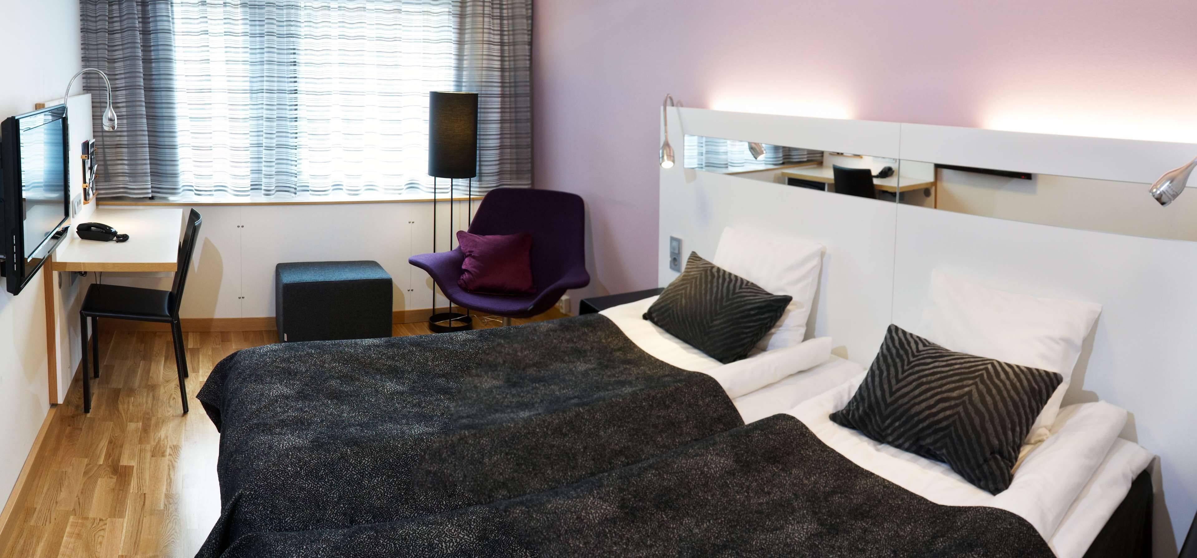 Una habitación de hotel con una cama, un escritorio, una silla y un espejo grande en la pared.