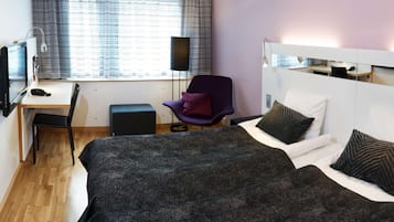 Una habitación de hotel con una cama, un escritorio, una silla y un espejo grande en la pared.