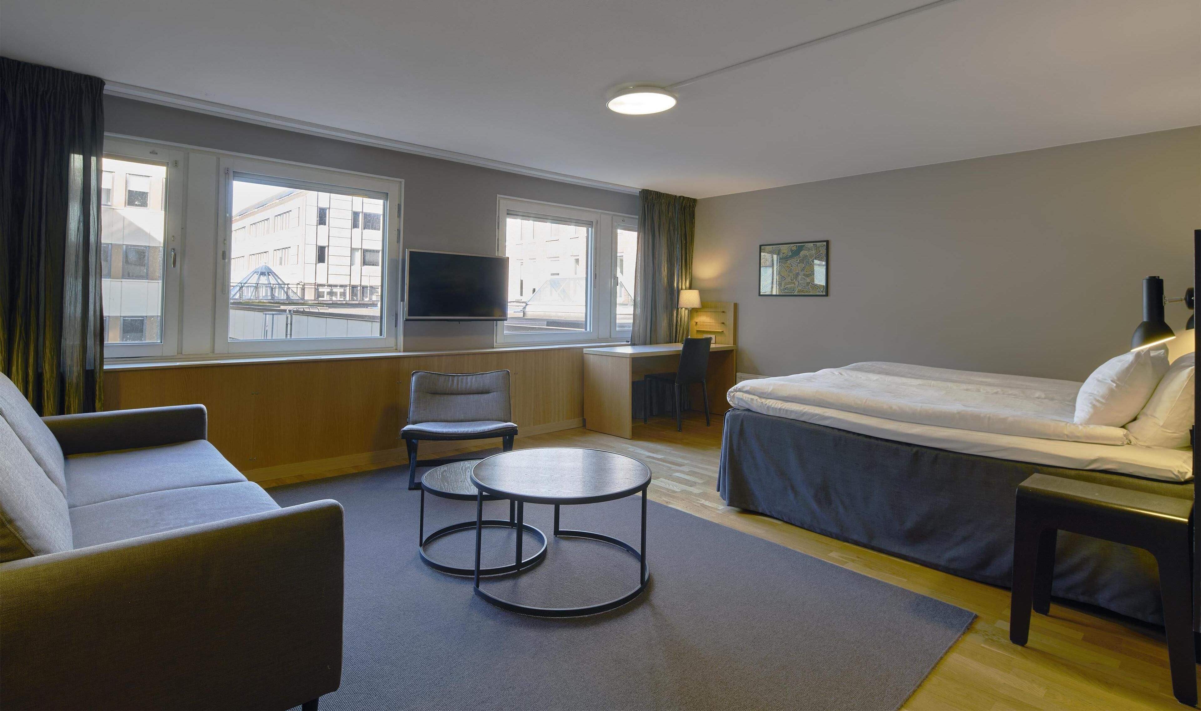 Une chambre d’hôtel équipée d’un lit, d’un bureau, d’une chaise, d’une petite table et d’un téléviseur.
