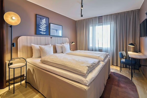 Una habitación de hotel moderna con una cama grande, mesitas de noche, un escritorio y una silla.