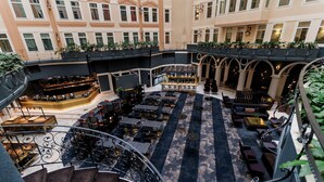 Un amplio atrio con una zona de bar central, diferentes opciones de asientos y una escalera que conduce a niveles superiores.