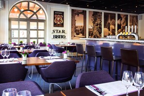 A restaurant with tables set for dining, a bar area, and a large window with a view.