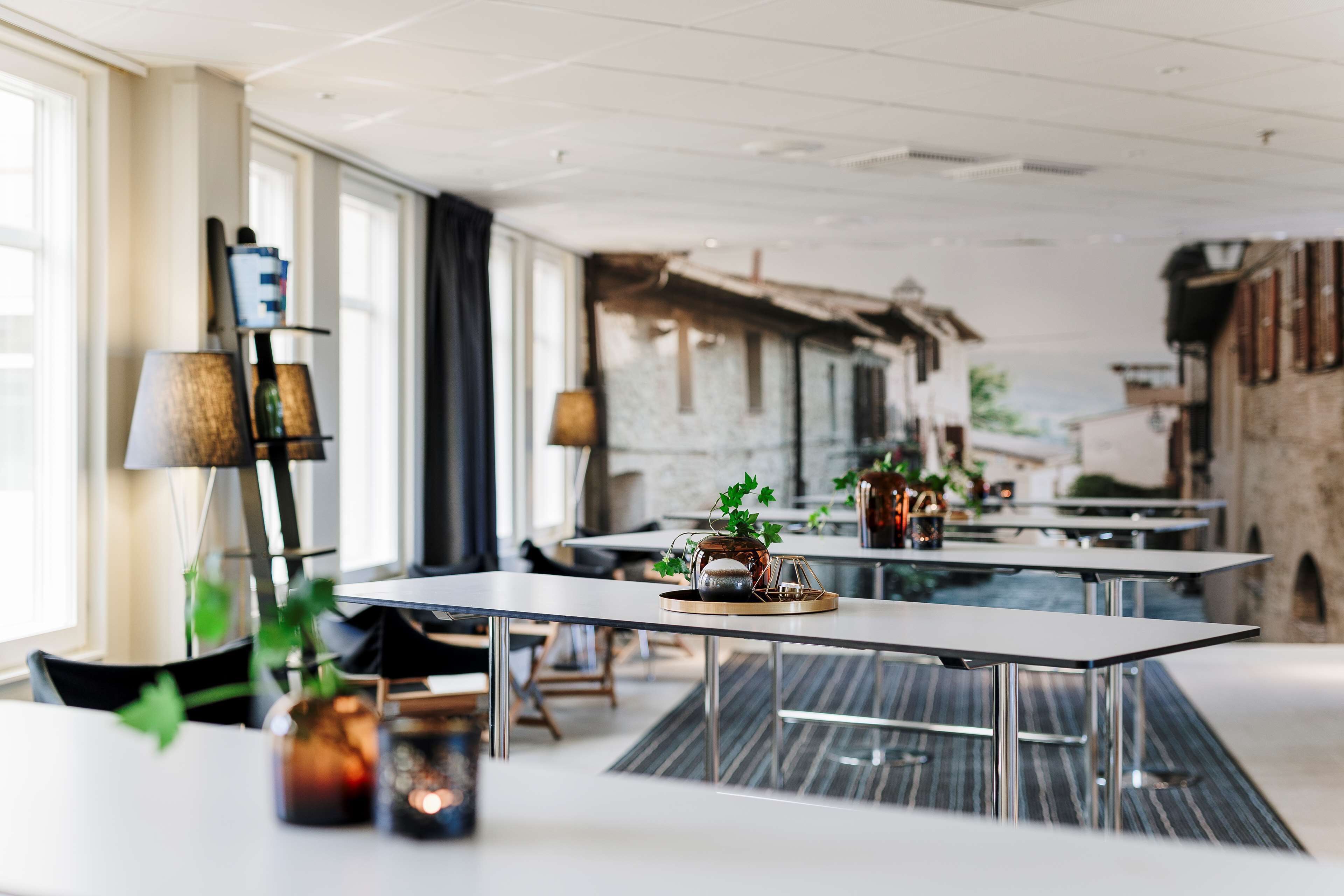 A modern dining area with tables, chairs, and decorative plants.