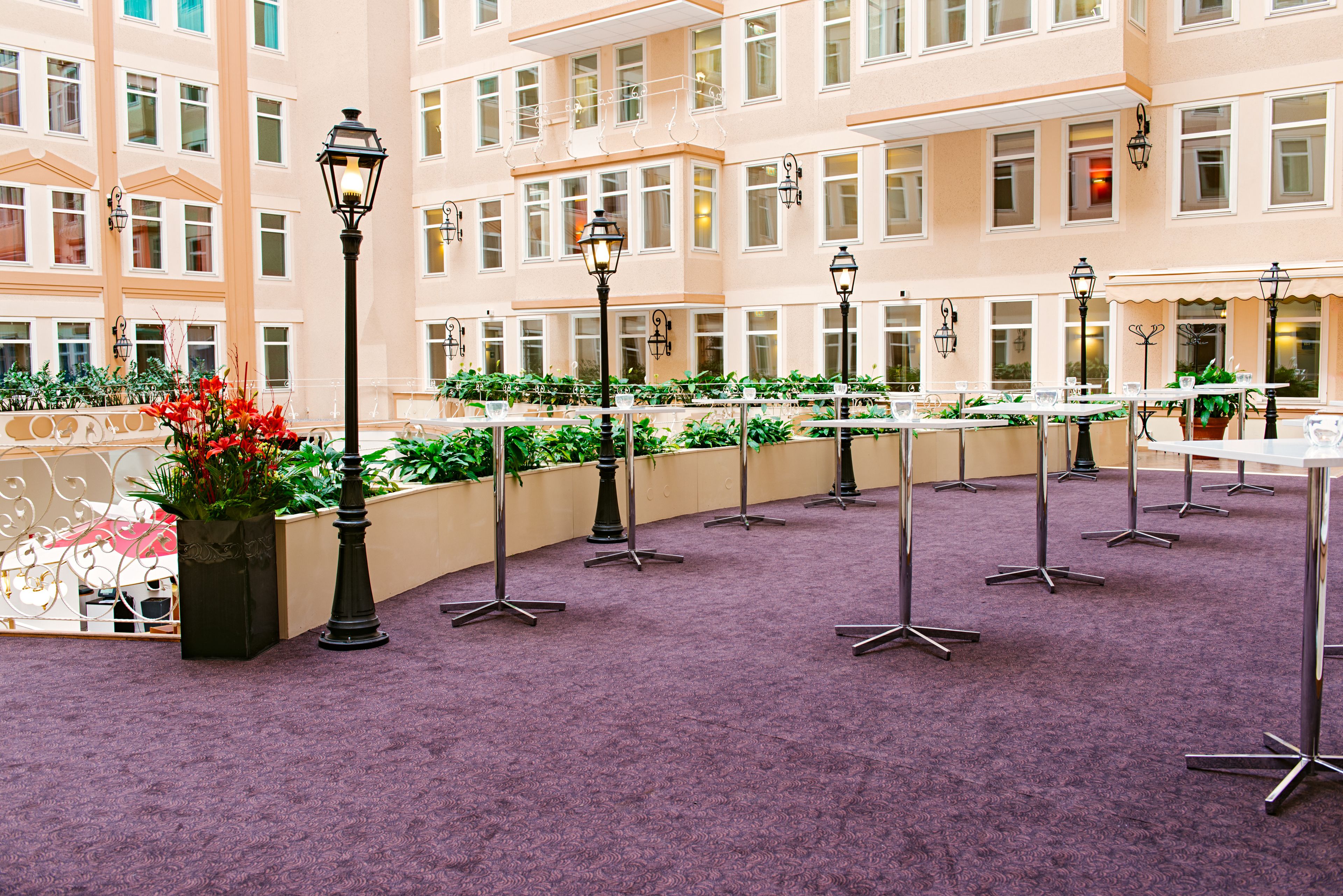 A hotel atrium with a purple carpet, outdoor seating area, and potted plants.