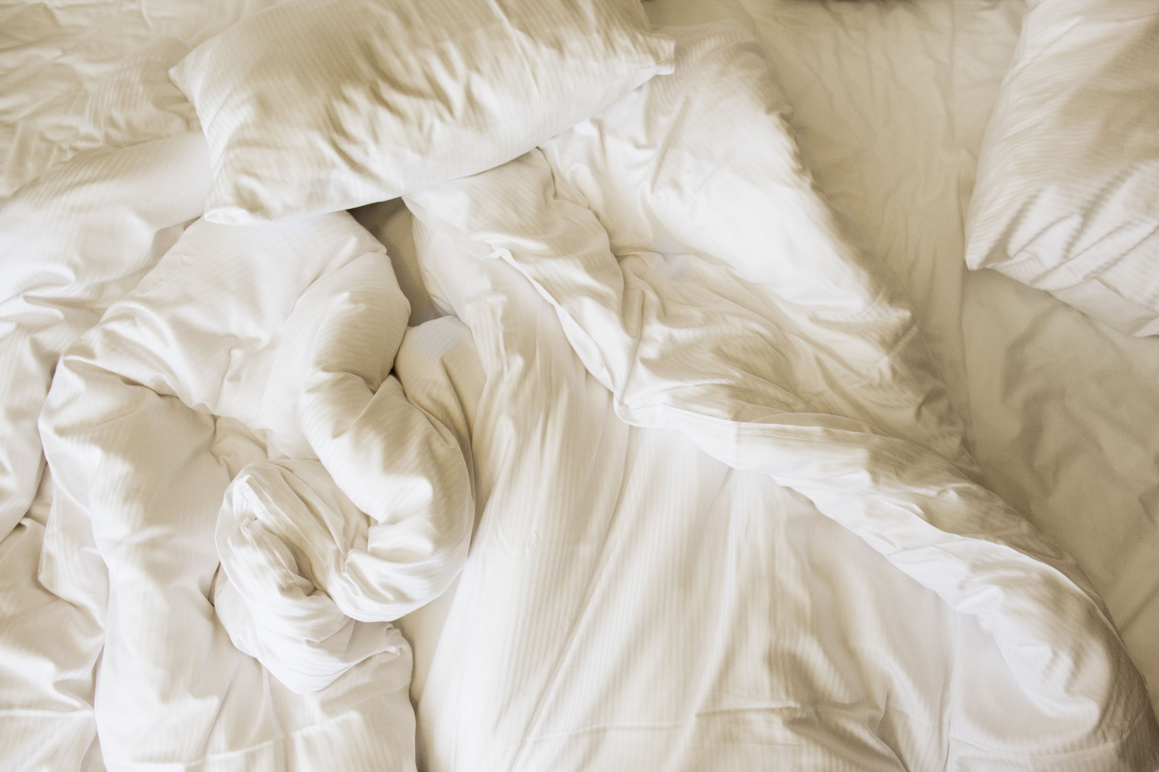 A bed with white bedding and pillows.