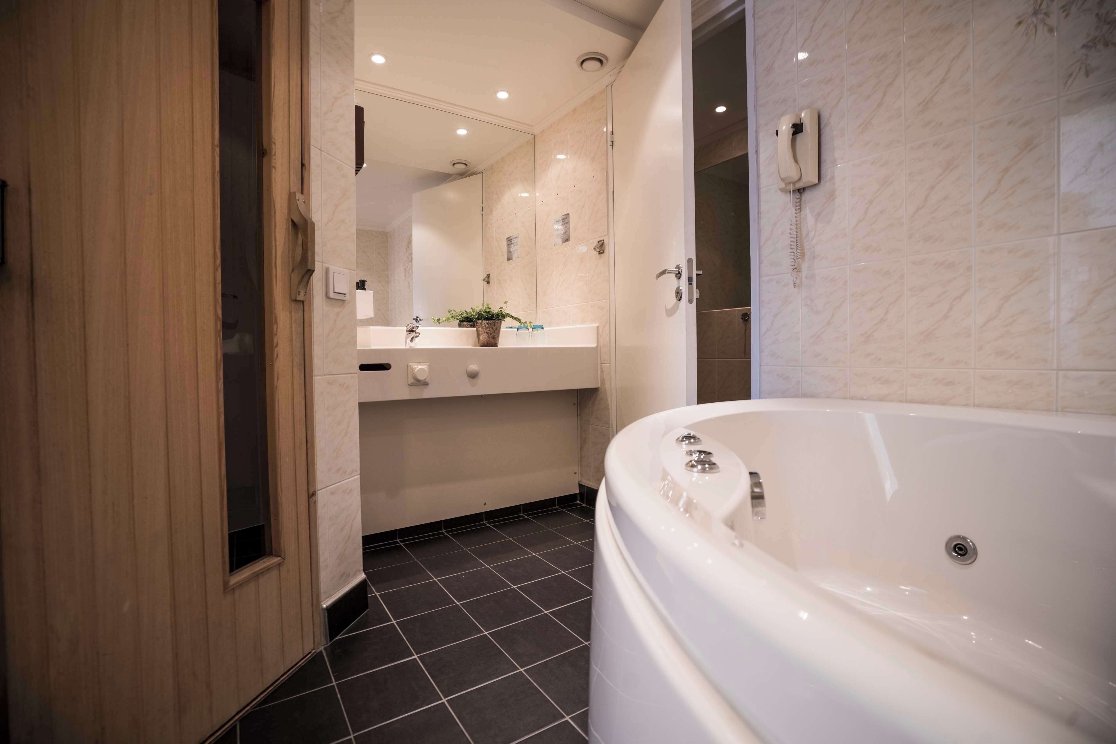 Une salle de bain moderne avec une grande baignoire, un meuble-lavabo avec un miroir et un téléphone.