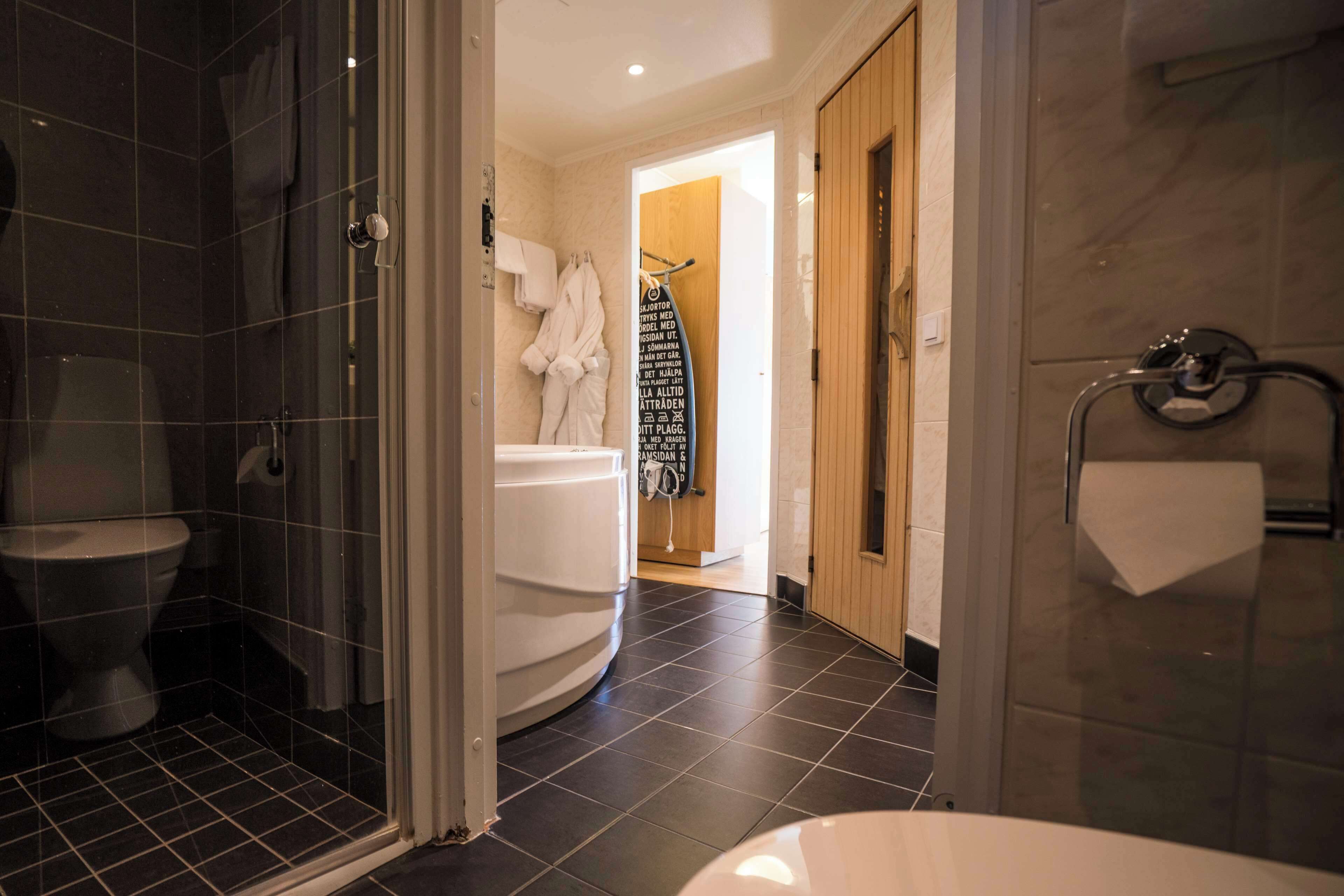 Un baño moderno con cabina de ducha de vidrio, inodoro blanco y una bañera grande.