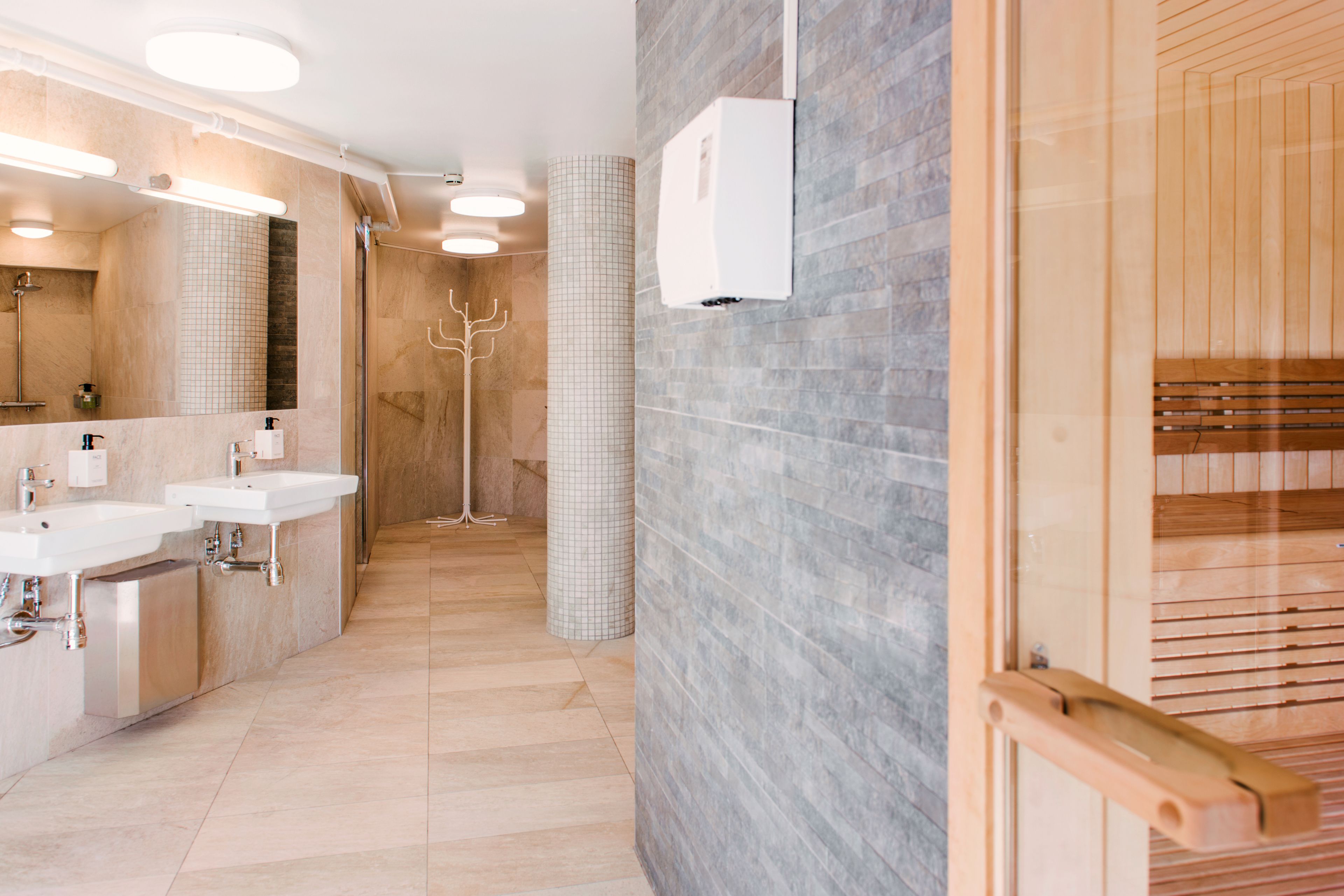 Un baño moderno con dos lavamanos, un espejo y una zona de ducha.