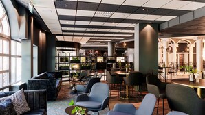 Un moderno hall de hotel con zonas de estar, un mostrador de recepción y vistas al interior.