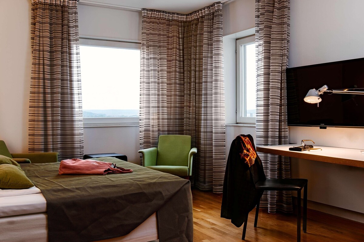 Una habitación de hotel con cama, escritorio, silla y televisor.
