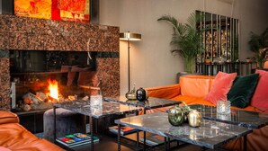 Un rincón de descanso acogedor con chimenea, asientos de cuero y un letrero de neón que dice "Plaza".