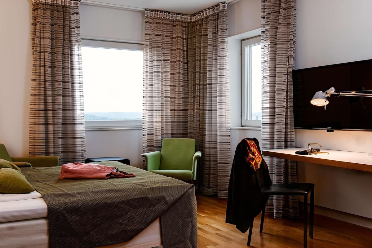 A hotel room with a bed, a desk, a chair, and a TV.
