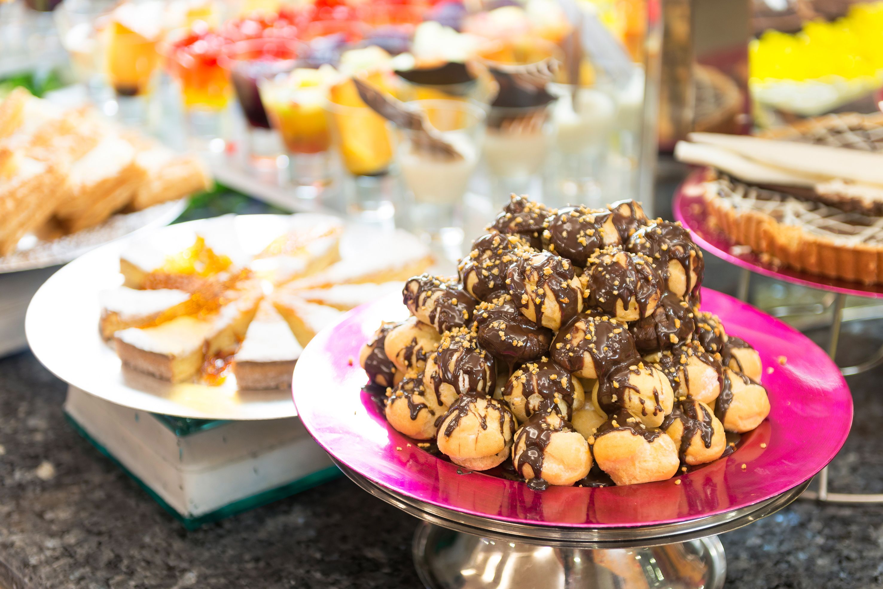 A buffet with various desserts, including chocolate-covered pastries and fruit tarts.