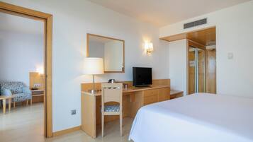 Habitación de hotel con cama, escritorio, silla, televisor, espejo y armario.