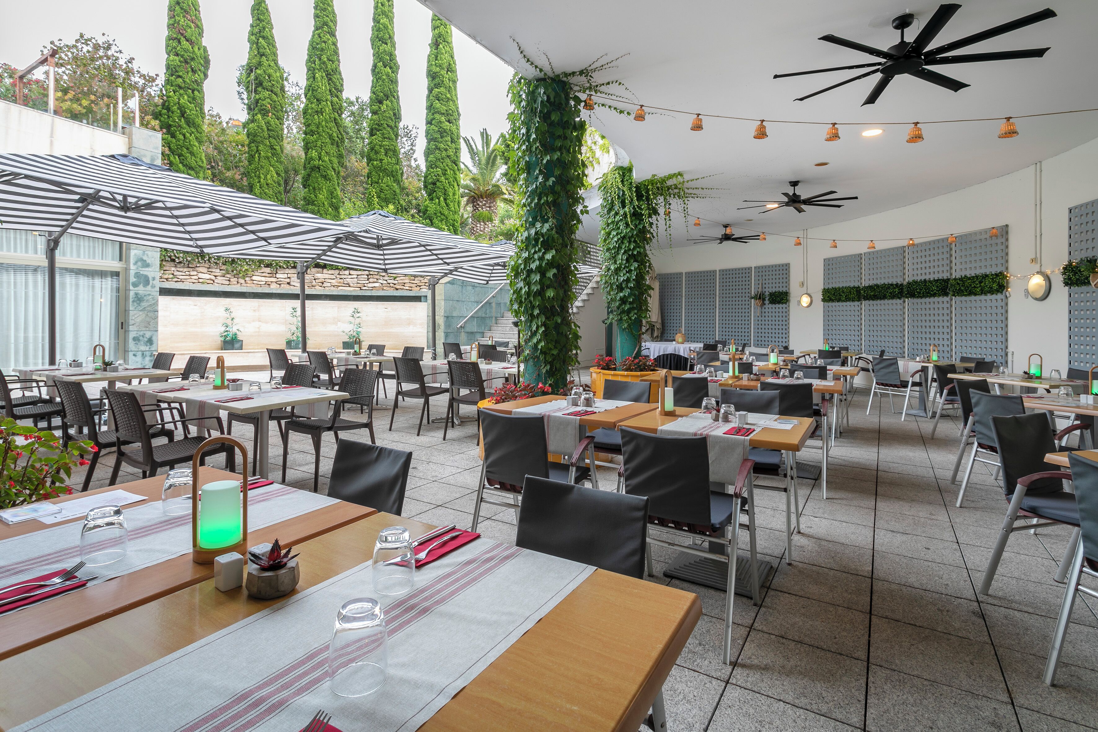 Ein geräumiges Restaurant mit hohen Decken, mehreren Tischen und Stühlen sowie Deckenventilatoren.