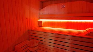 A sauna with wooden benches and a bench with a towel.