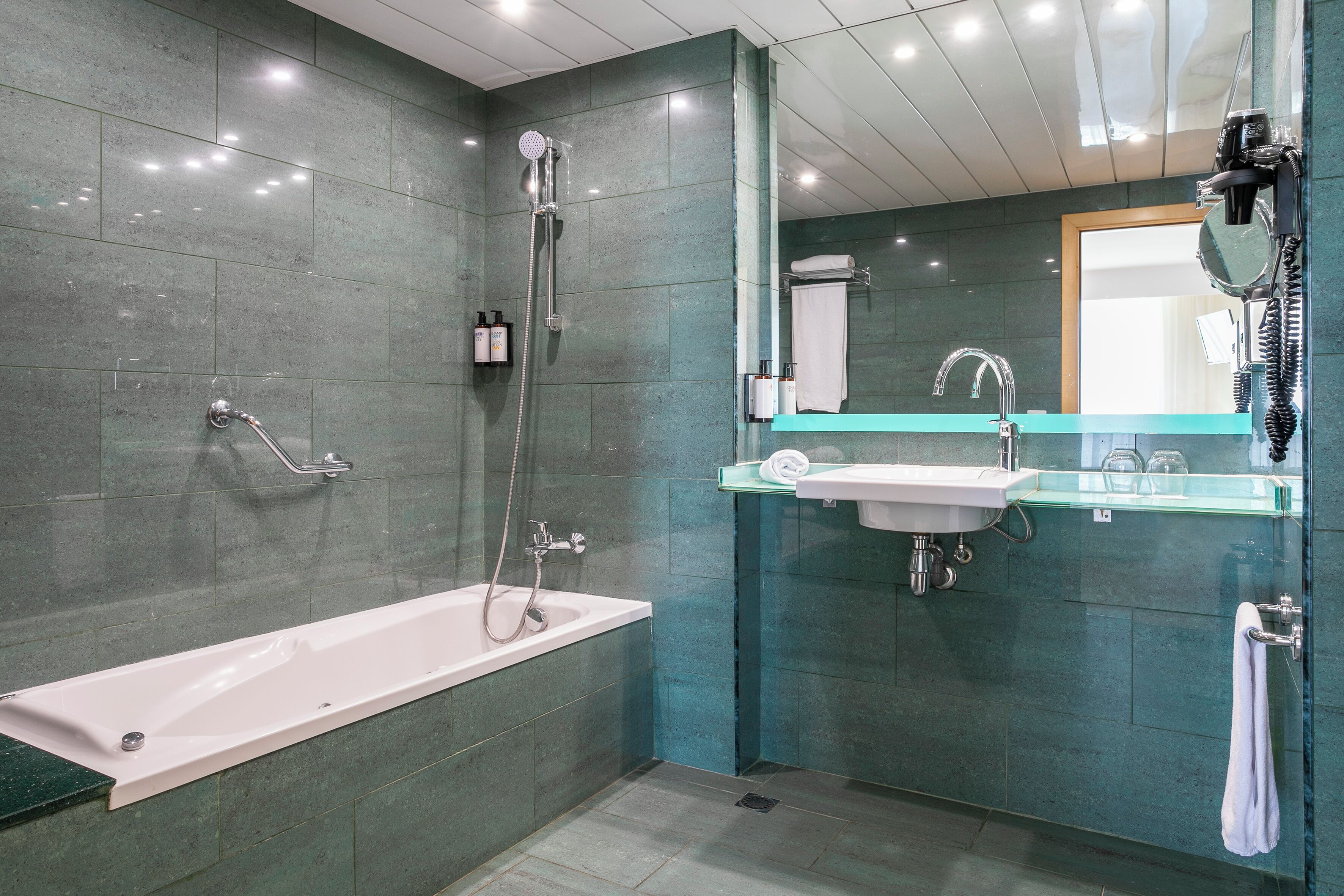 A modern bathroom with a bathtub, shower, and sink.