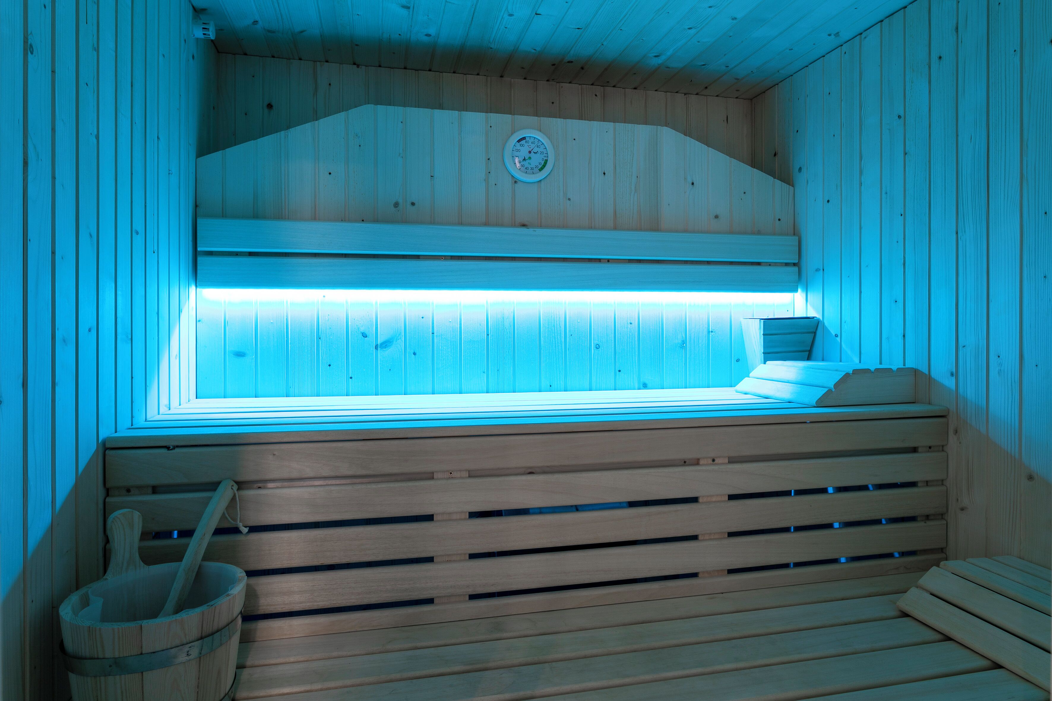 A sauna with wooden slats, a bench, and a wooden bucket.