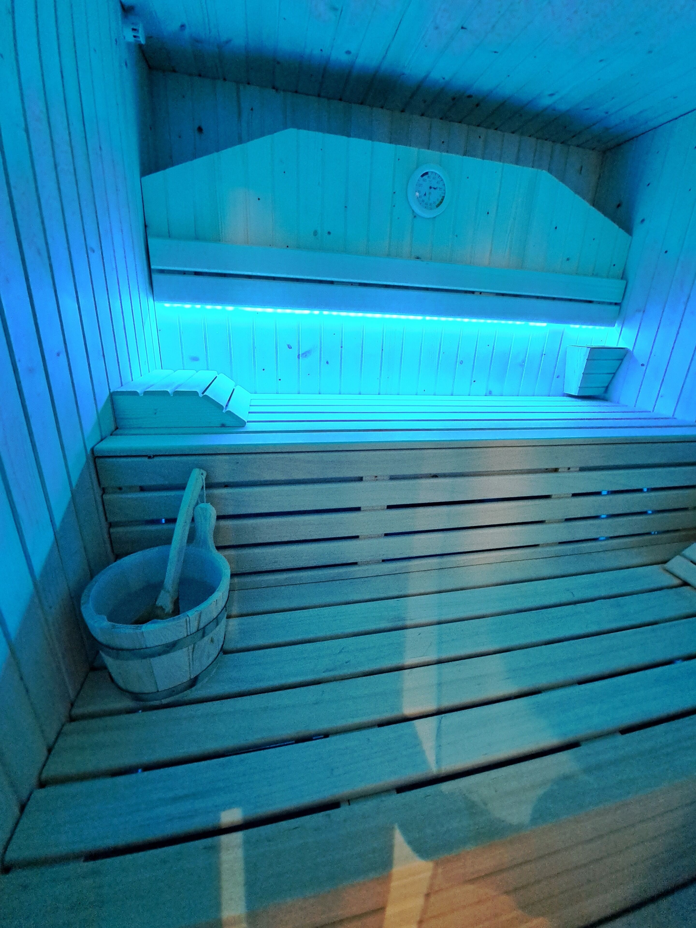 Una sauna con bancos de madera y una pileta de piedra.