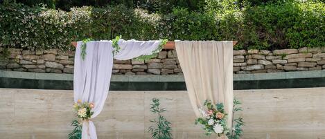 A red carpet aisle with white chairs and red sashes, leading to an altar decorated with flowers and drapes.