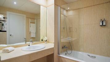 Un baño moderno con ducha envuelta en vidrio, lavamanos y un espejo grande.