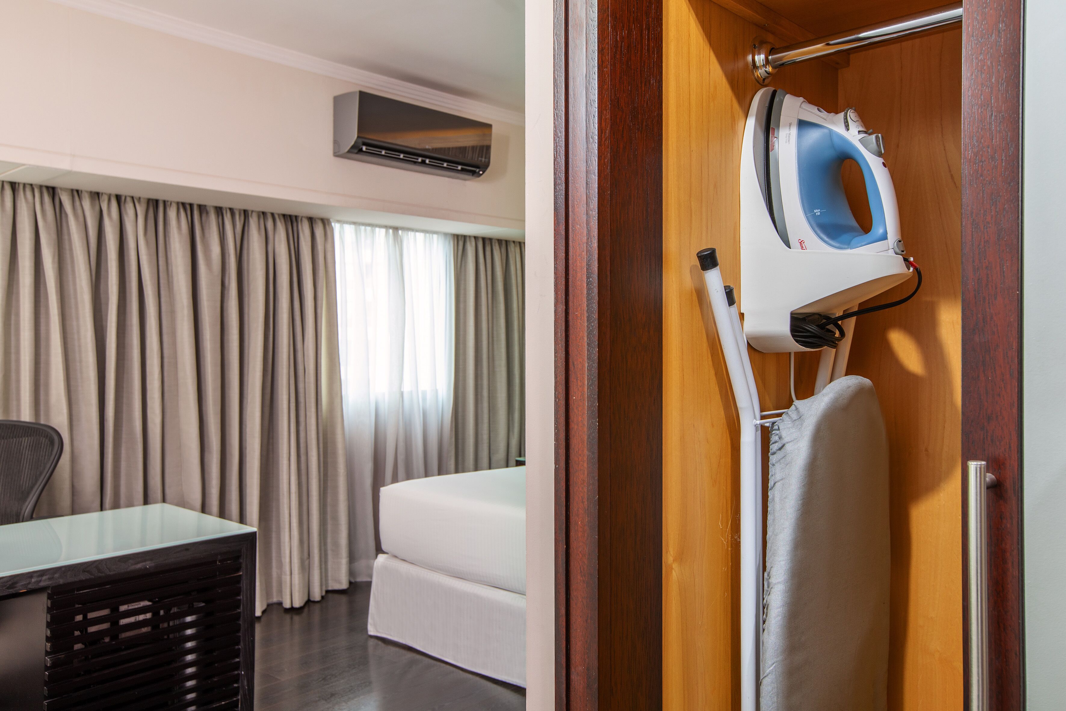 Una camera d'hotel con un letto, una scrivania e un asse da stiro con ferro da stiro.