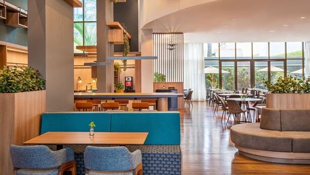 Un restaurante moderno con techos altos, muebles de madera y amplios ventanales.