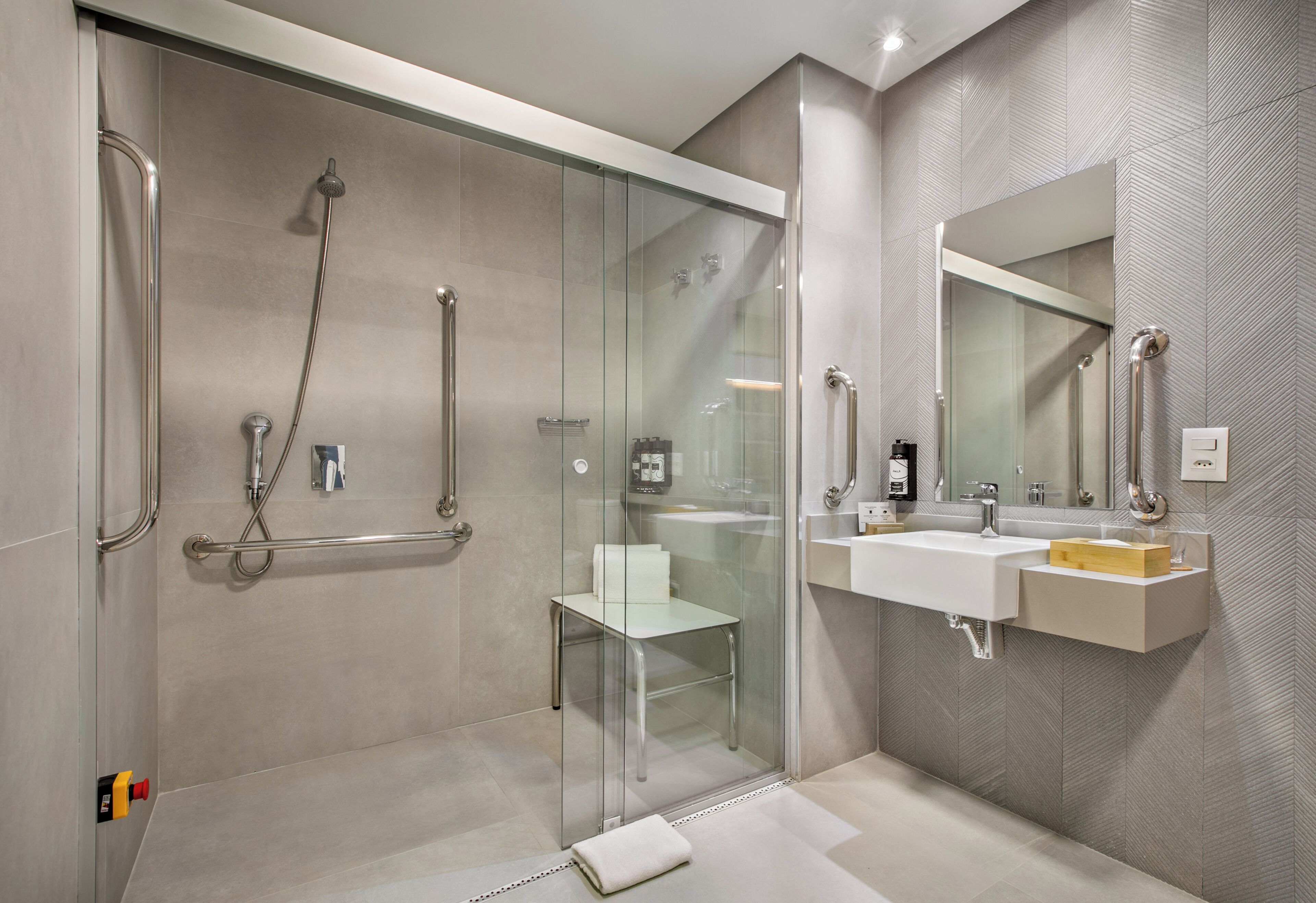 A modern bathroom with a glass-enclosed shower, a white sink, and a large mirror.