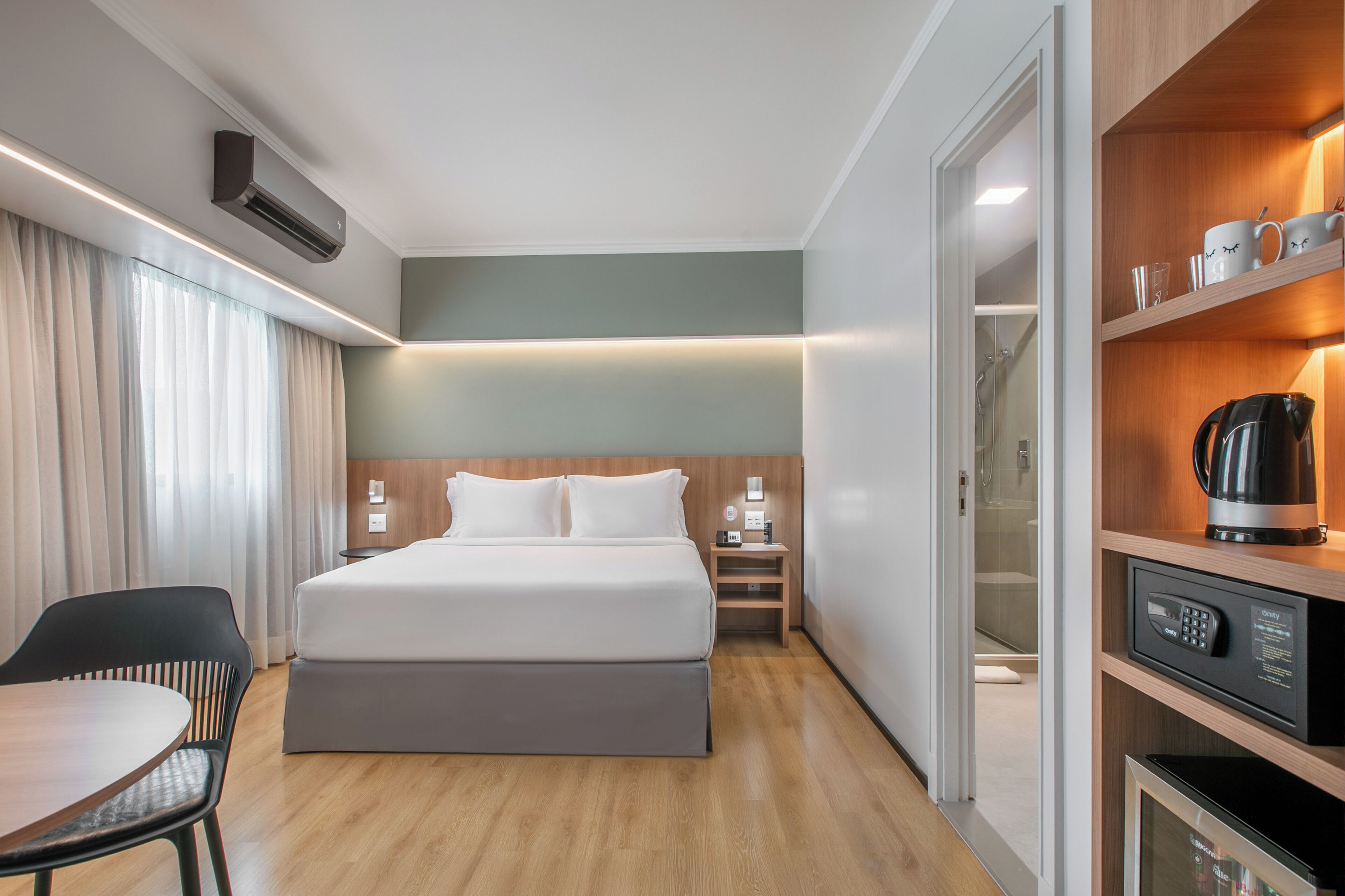A hotel room with a bed, bedside table, and a built-in coffee maker.
