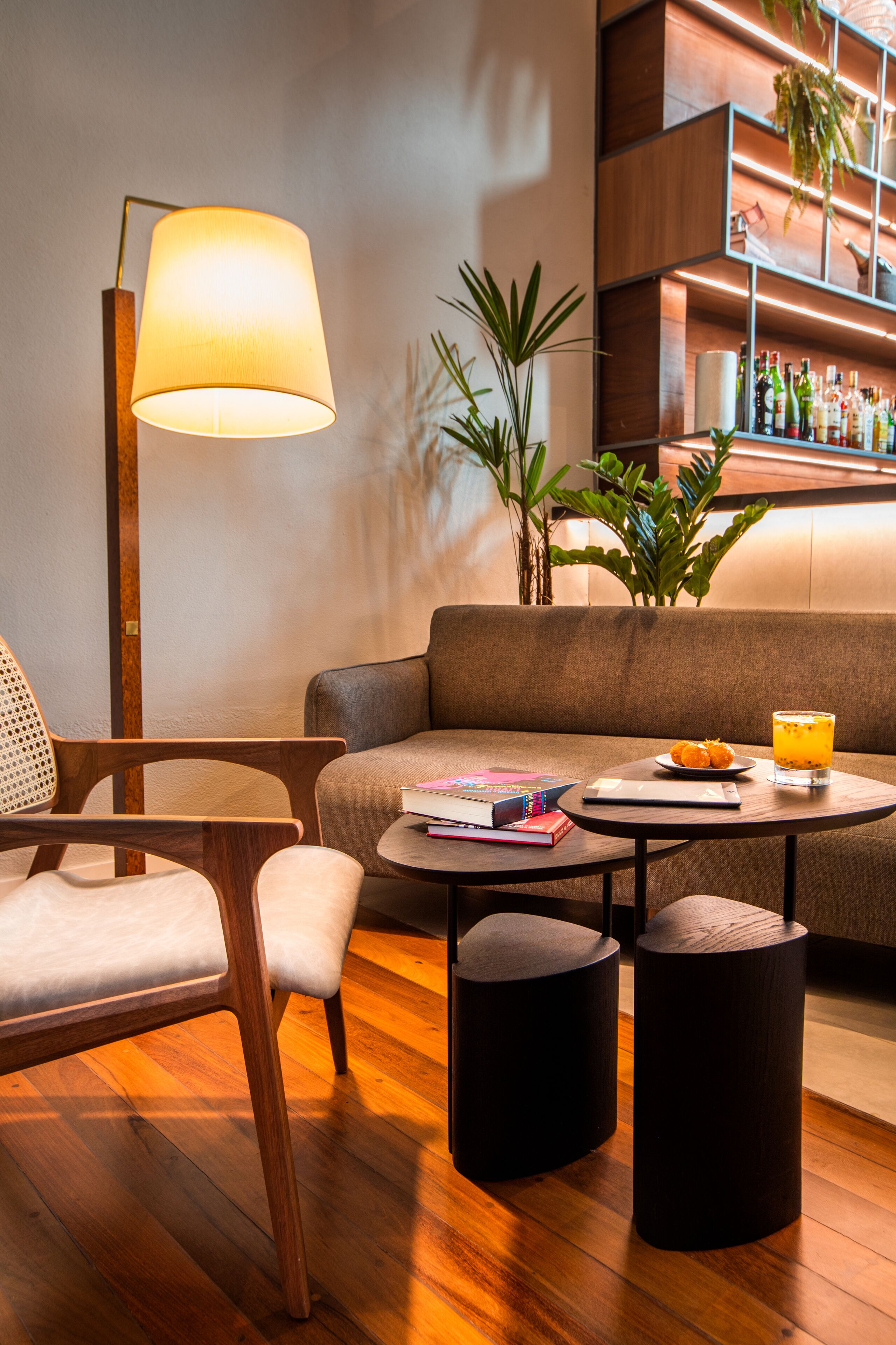 A modern living room with a sofa, two round tables, a floor lamp, and a bar area with shelves.