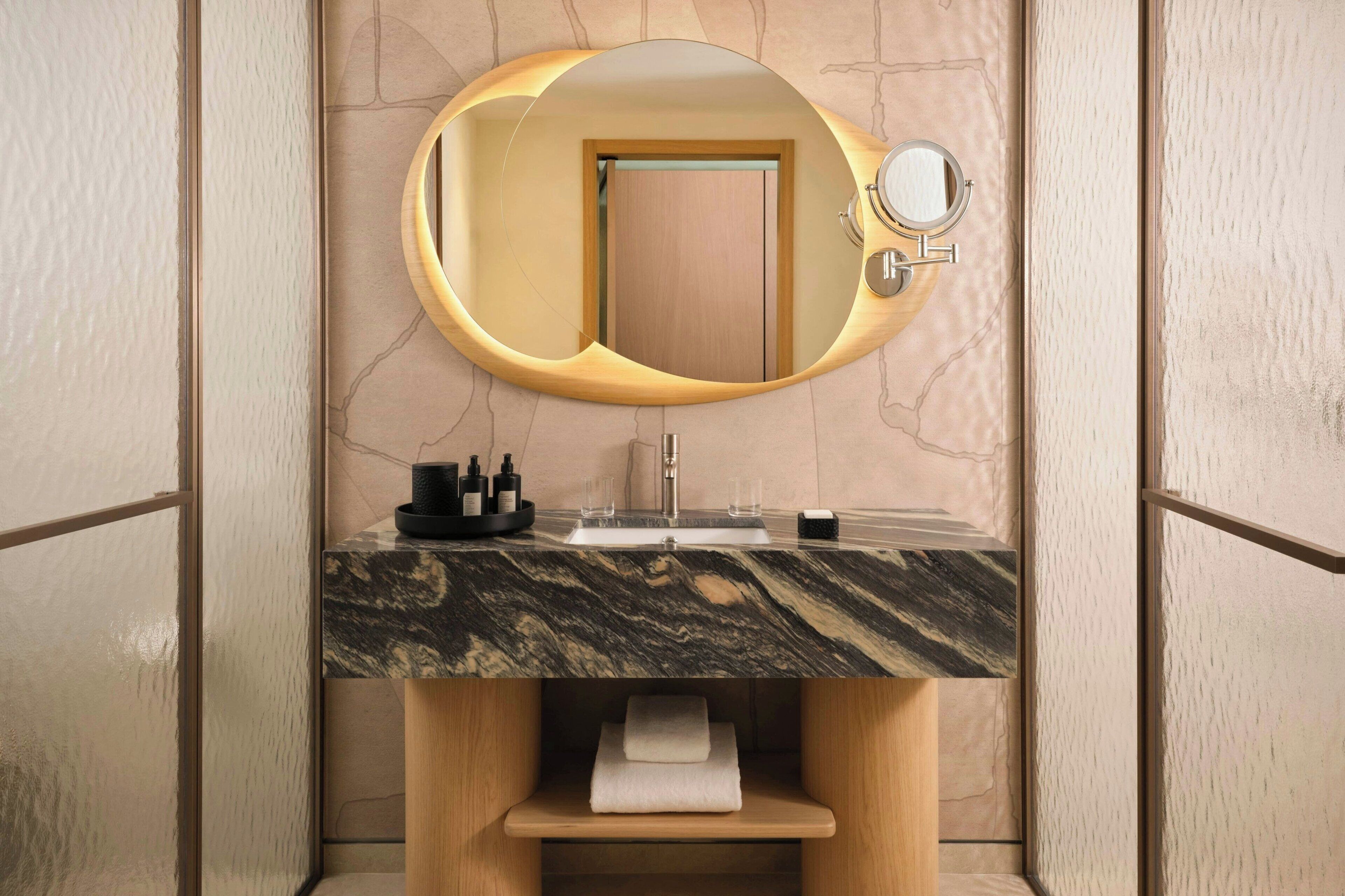 A bathroom with a marble sink, wooden vanity, and a mirror with a wooden frame.