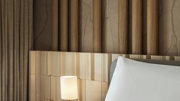 A hotel room with a bed, a nightstand with a lamp, and a headboard with vertical wooden panels.