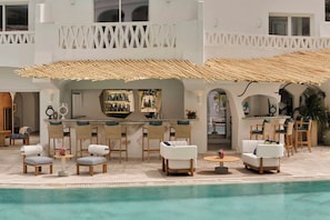 Zona junto a la piscina con mobiliario exterior, un bar y vistas a la piscina.