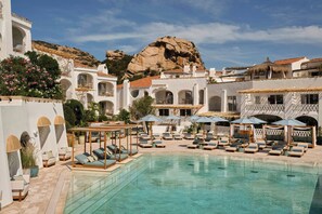 A poolside area with lounge chairs and umbrellas, a clear pool, and a mountainous backdrop. - W Sardinia - Poltu Quatu (Arzachena)