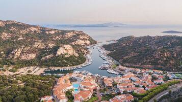 A coastal town with a marina, terraced houses, and a mountainous backdrop.