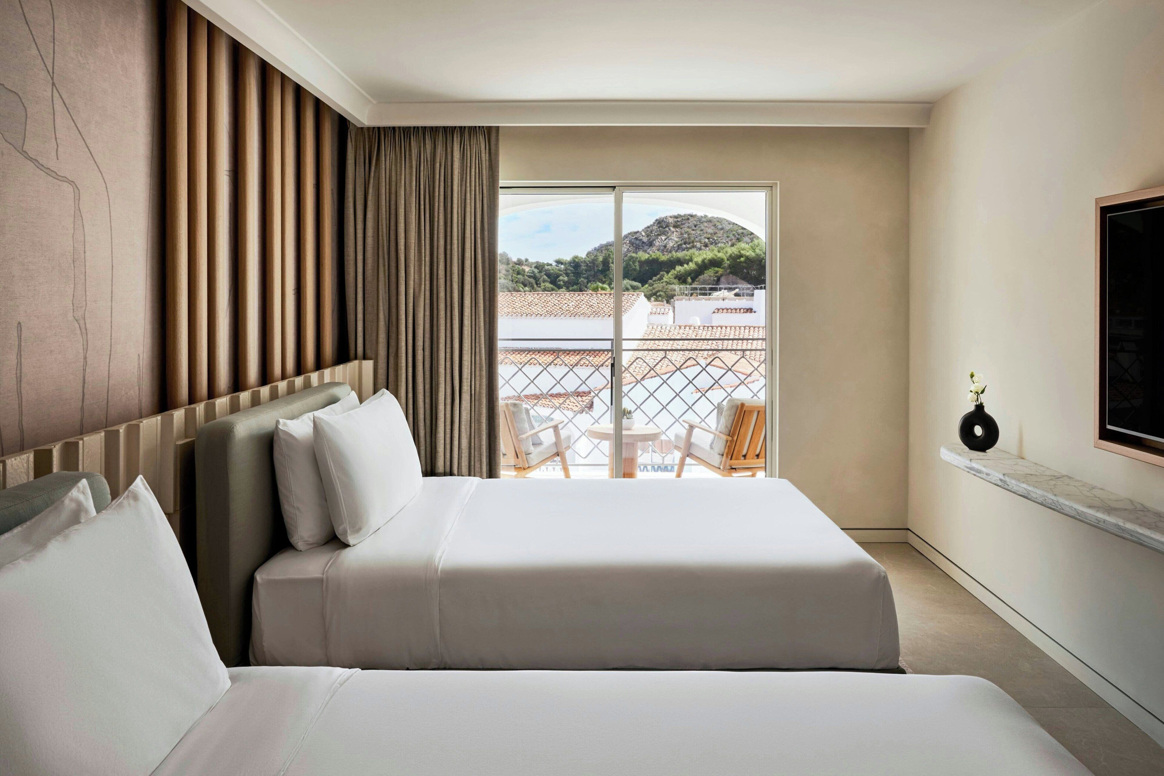 Una habitación de hotel con una cama grande, vistas al mar y un balcón con sillas.