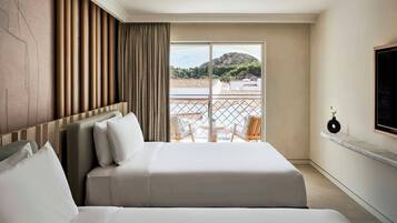Una habitación de hotel con una cama grande, vistas al mar y un balcón con sillas.