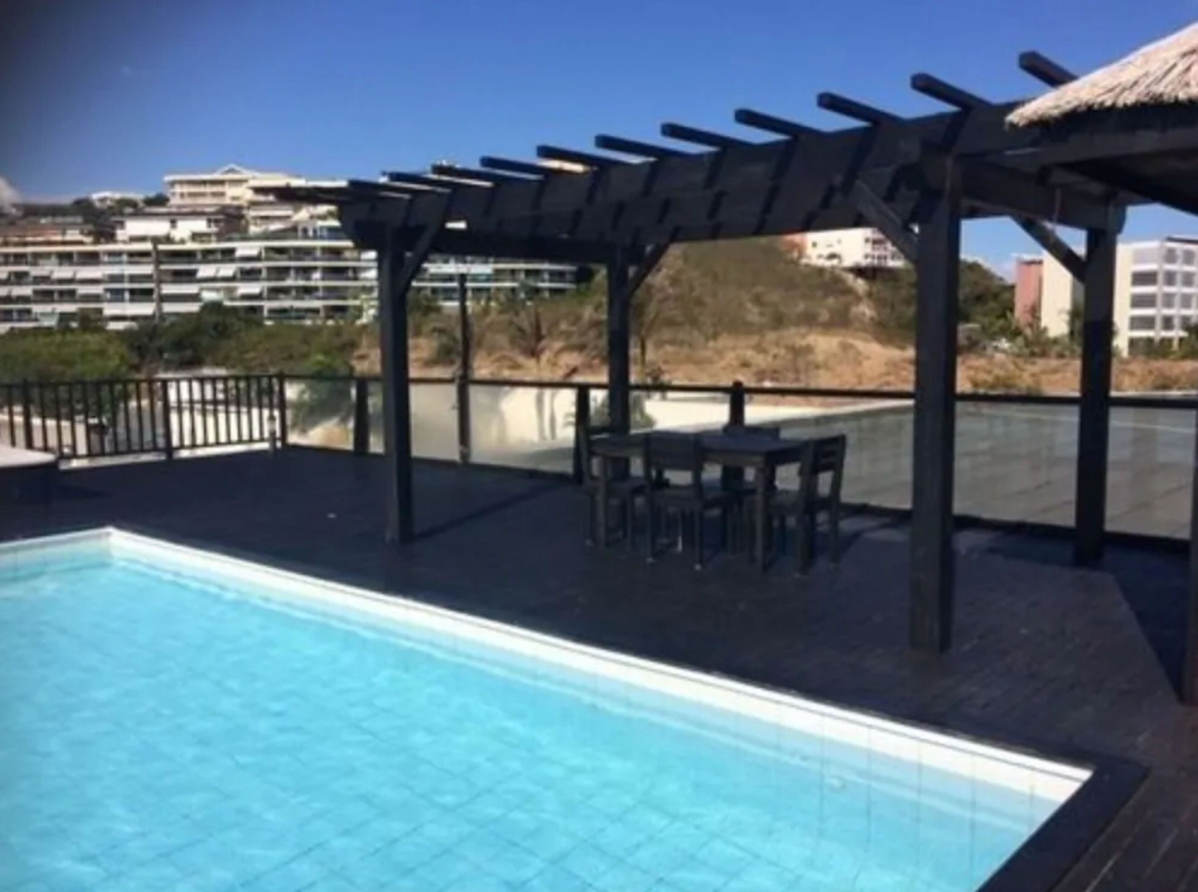 A swimming pool with a pergola and outdoor seating area.