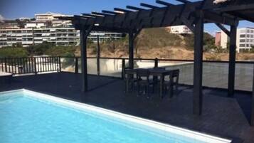 A swimming pool with a pergola and outdoor seating area.