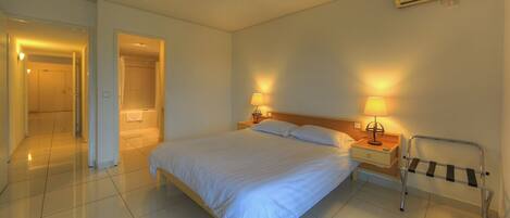 Habitación de hotel con cama, lámparas de noche, una silla de ruedas y zona de ducha.