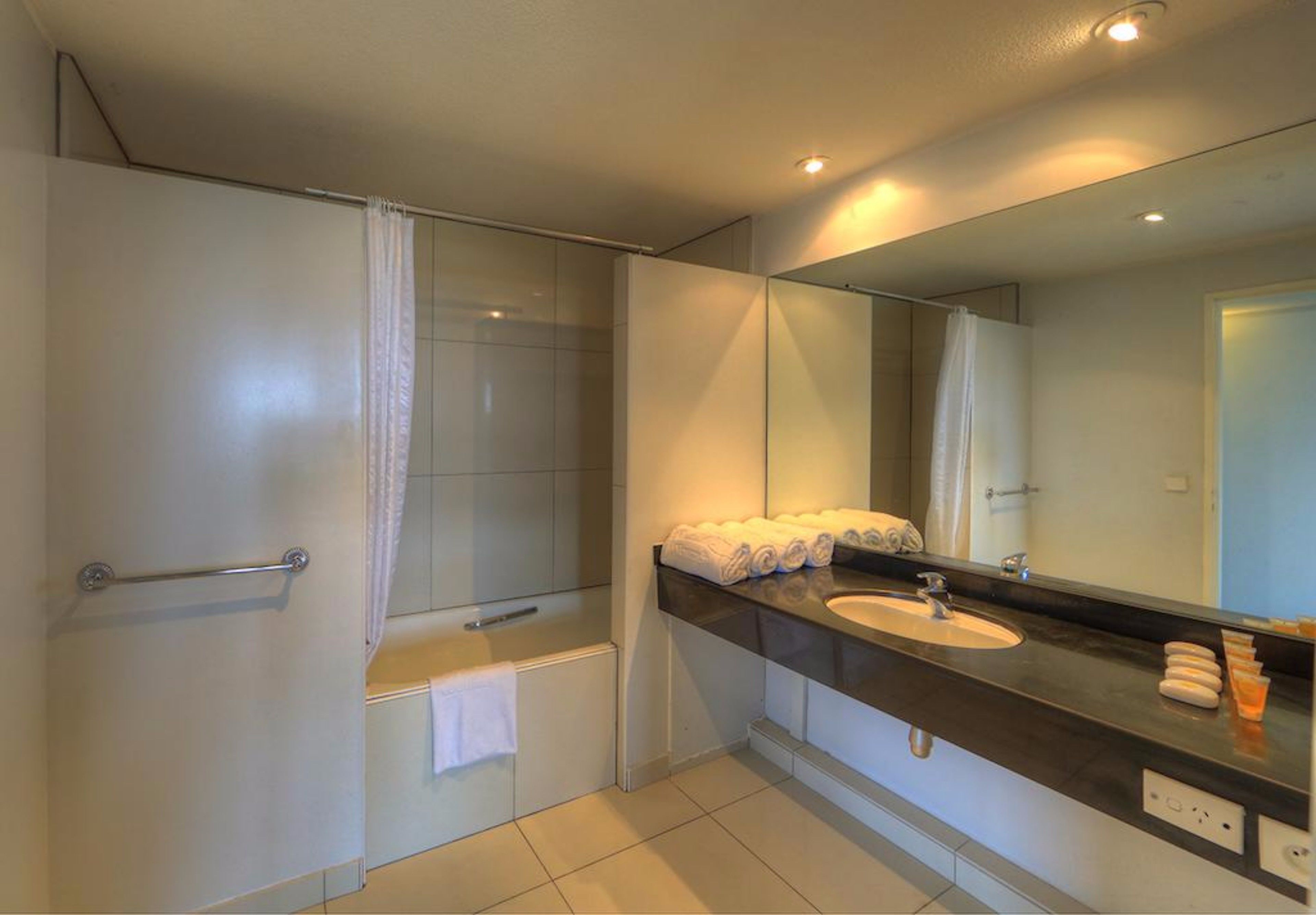 A modern bathroom with a shower, a sink, and a large mirror.