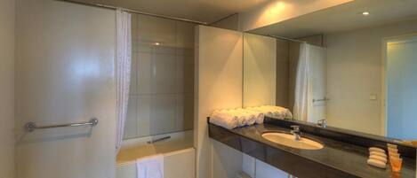 A modern bathroom with a shower, a sink, and a large mirror.