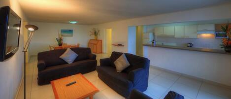 A compact living space with a sofa set, a small table, and a kitchen area.
