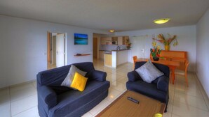 A living room with two sofas, a coffee table, and a dining area with a table and chairs.