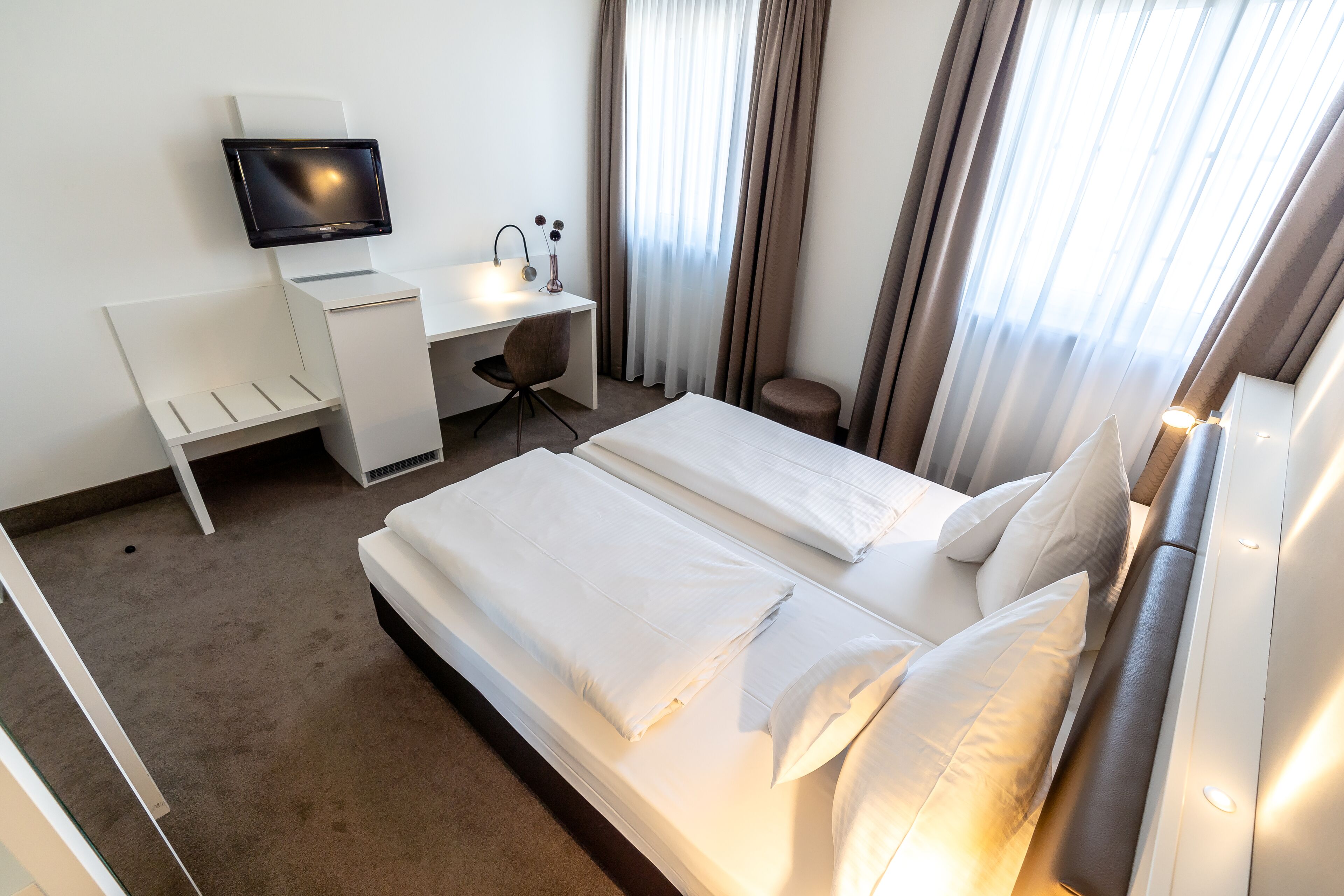 Une chambre d’hôtel avec un lit, un bureau équipé d’un ordinateur et une chaise.