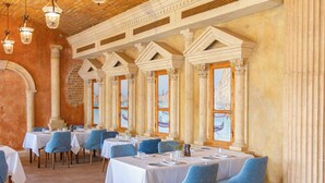 A restaurant with white tablecloths, blue chairs, and columns.