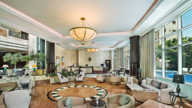 A spacious lobby with a central circular seating area, large windows, and a reception desk.