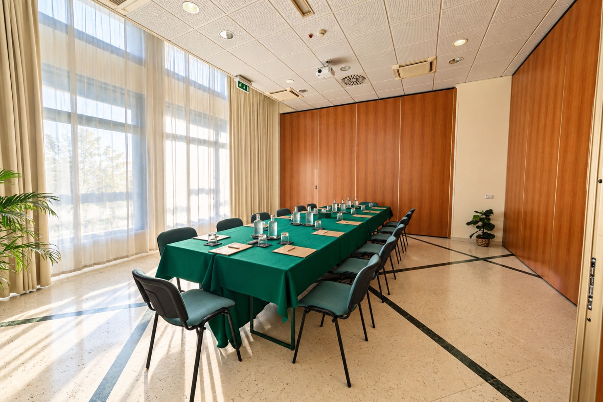 Un salón de conferencias con una larga mesa, sillas y una planta en maceta.