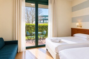 Una habitación de hotel con una cama, un sofá y vistas al exterior.