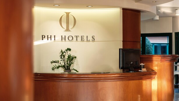 A reception desk with a logo and the name "PHI HOTELS" on the wall. - Phi Hotel Emilia (Ozzano dell'Emilia)